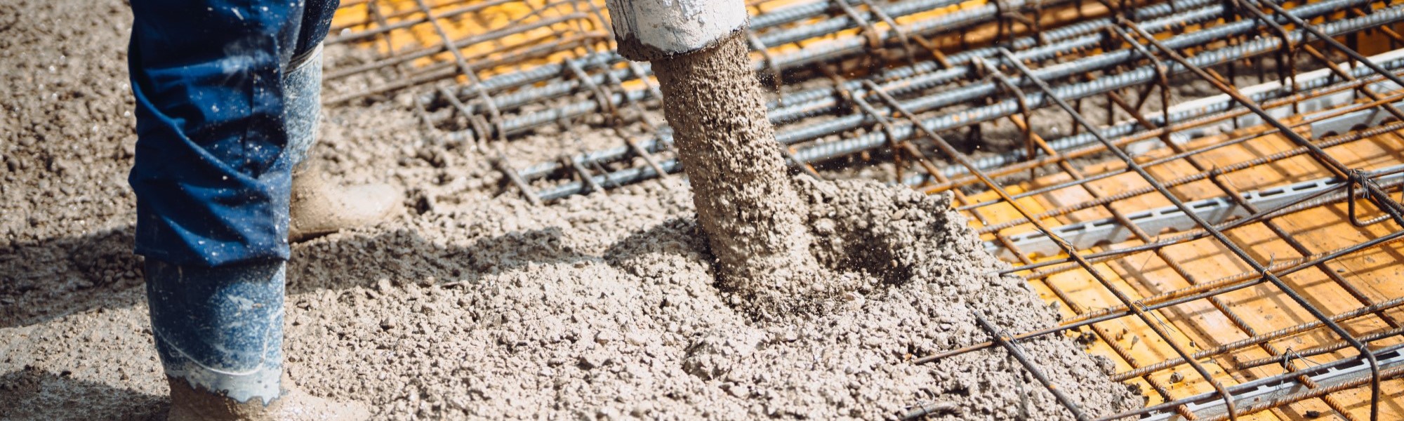 man on construction site, worker pouring concrete with pump tube
